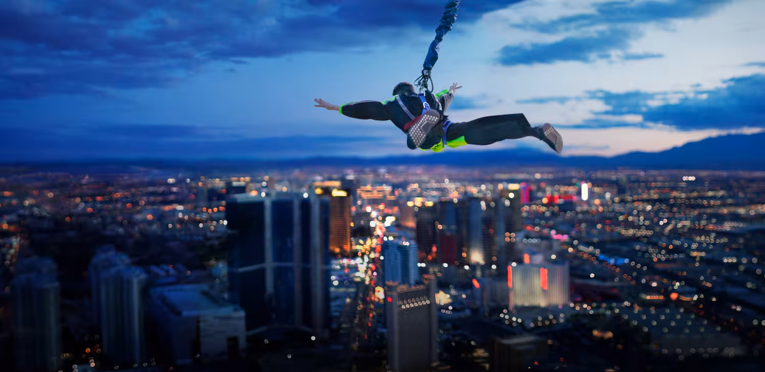 SkyJump Person skydiving from a tower attraction with city lights below and dramatic evening skyline view